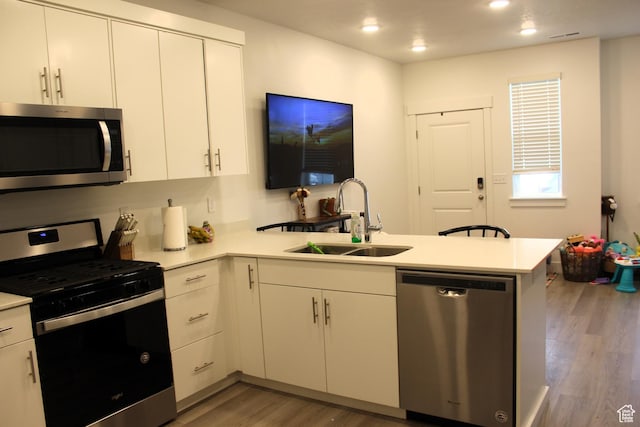 953 N 900 W, Tremonton, UT 84337 - kitchen with a peninsula, light wood-style flooring, a sink, light countertops, and appliances with stainless steel finishes