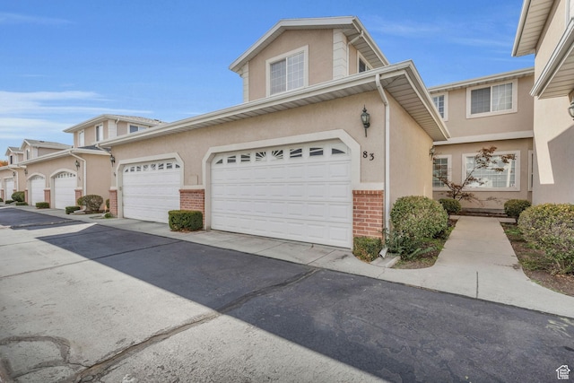 83 N 380 W, Orem, UT 84057 - view of front facade with brick siding, a garage, stucco siding, and aphalt driveway