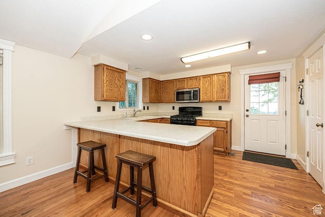 325 E 100 N, Willard, UT 84340 - kitchen with stainless steel microwave, black gas range oven, a peninsula, brown cabinetry, and light countertops
