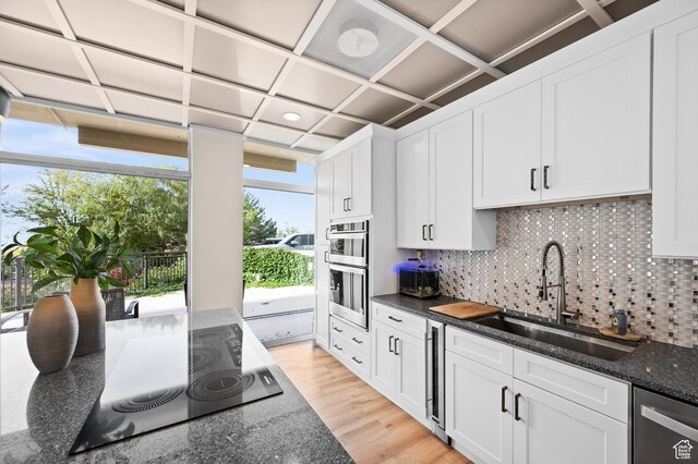 875 S Donner Way E Unit 111, Salt Lake City, UT 84108 - kitchen with dark stone counters, white cabinetry, decorative backsplash, black electric stovetop, and a sink
