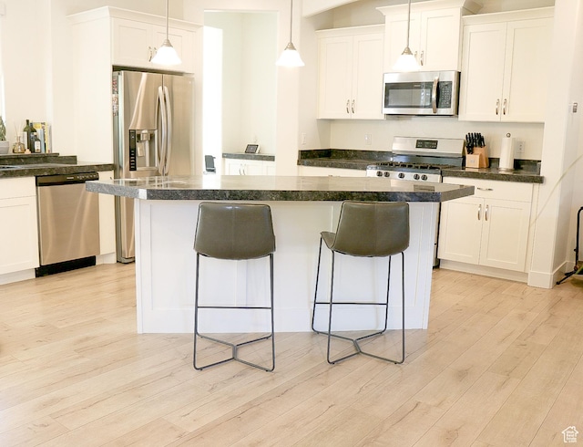 4172 S Kiera Hill Ln E, Millcreek, UT 84107 - kitchen with appliances with stainless steel finishes, a kitchen bar, light wood-style flooring, dark countertops, and white cabinetry