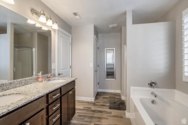 bathroom featuring visible vents, wood finished floors, a garden tub, and a sink