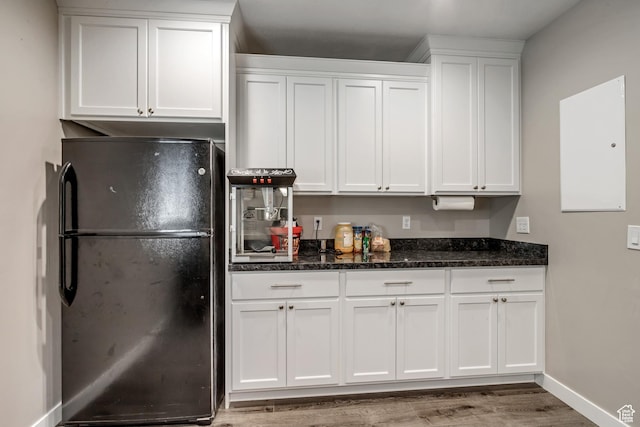 kitchen featuring freestanding refrigerator, light wood-style floors, white cabinetry, and dark stone counters