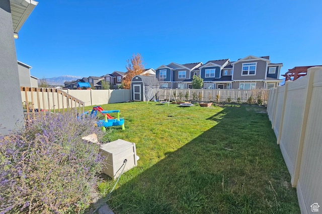 view of yard featuring a fenced backyard, an outbuilding, a storage shed, and a residential view