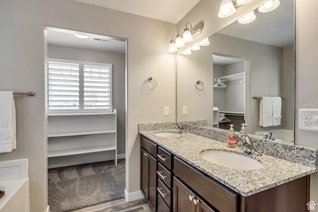 bathroom featuring double vanity, visible vents, a washtub, and a sink