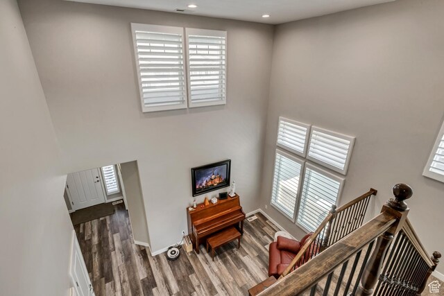staircase with recessed lighting, wood finished floors, a towering ceiling, and baseboards