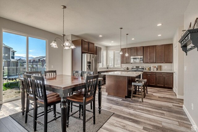 dining space with baseboards, a notable chandelier, light wood finished floors, and recessed lighting