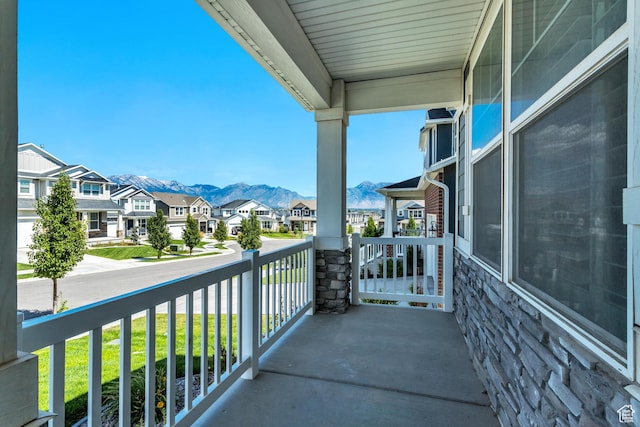 balcony featuring covered porch, a mountain view, and a residential view