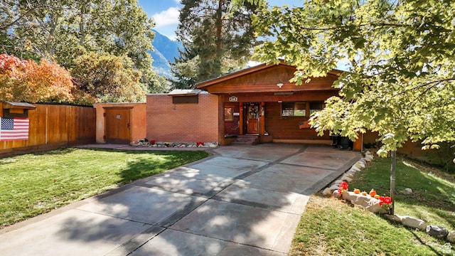 view of front facade with brick siding, a front yard, and fence