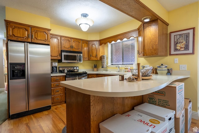 452 S 100 W, Salina, UT 84654 - kitchen featuring brown cabinetry, a peninsula, light wood-style floors, light countertops, and stainless steel appliances
