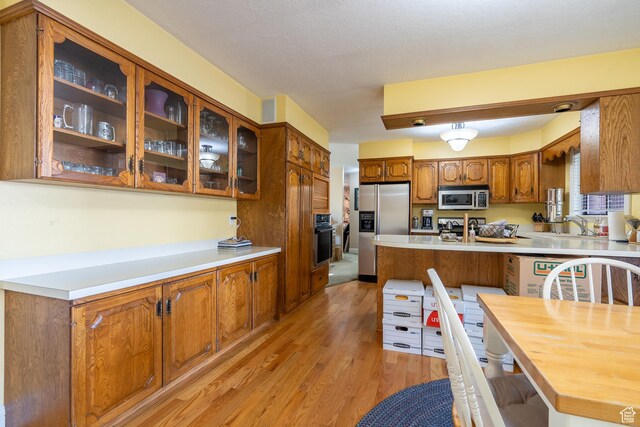 452 S 100 W, Salina, UT 84654 - kitchen with appliances with stainless steel finishes, light wood-style floors, light countertops, brown cabinetry, and glass insert cabinets