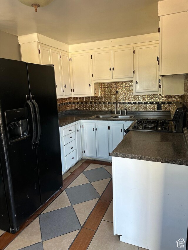 kitchen featuring a sink, white cabinetry, black refrigerator with ice dispenser, and dark countertops