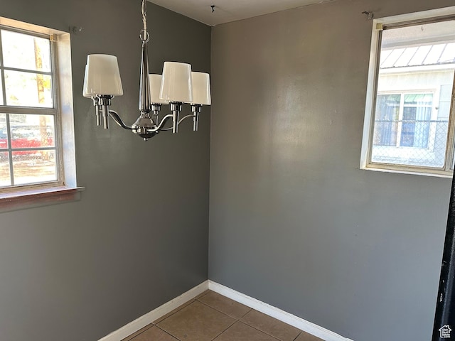 unfurnished room with an inviting chandelier, baseboards, tile patterned flooring, and a healthy amount of sunlight