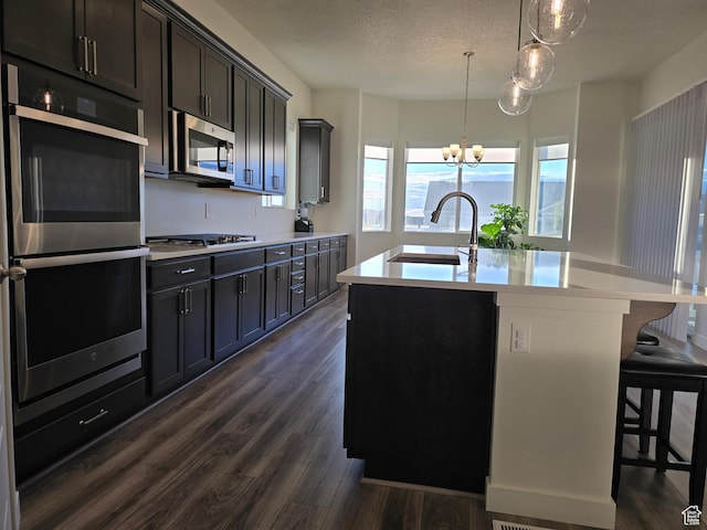 697 N 3275 W, Layton, UT 84041 - kitchen featuring stainless steel appliances, dark wood-style flooring, a chandelier, an island with sink, and light countertops