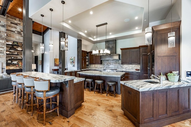 1159 Snow Berry St, Park City, UT 84098 - kitchen featuring a sink, wall chimney range hood, a spacious island, backsplash, and a kitchen bar