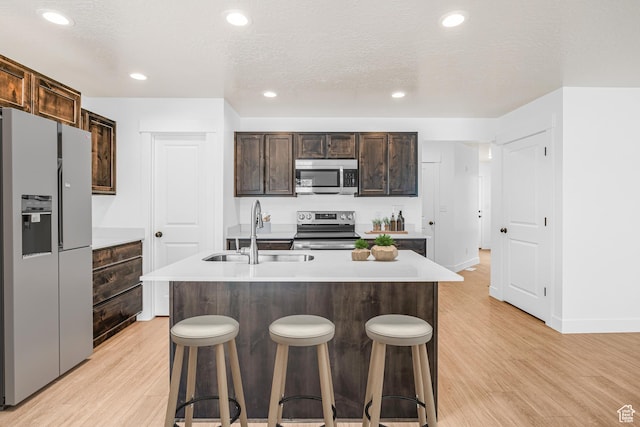 2003 S Freestone Blvd Unit 424, Santaquin, UT 84655 - kitchen with appliances with stainless steel finishes, light wood finished floors, a breakfast bar area, light countertops, and dark brown cabinets