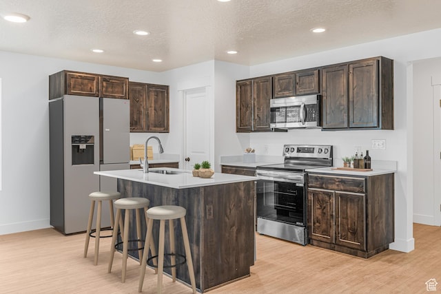 2003 S Freestone Blvd Unit 424, Santaquin, UT 84655 - kitchen with stainless steel appliances, a breakfast bar area, light wood-style flooring, dark brown cabinets, and an island with sink