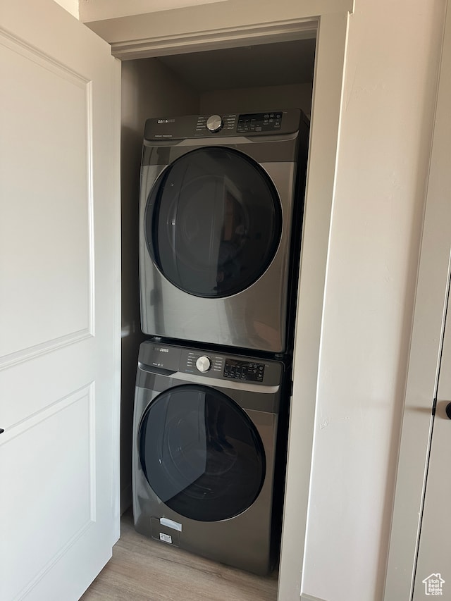 clothes washing area featuring light wood-type flooring and stacked washing maching and dryer