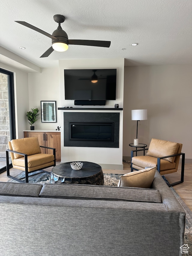 living room with ceiling fan, a textured ceiling, and hardwood / wood-style floors
