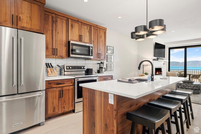 35 E 150 S Unit 102E, Garden City, UT 84028 - kitchen featuring stainless steel appliances, brown cabinets, open floor plan, light countertops, and a kitchen bar