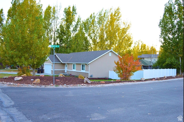 view of front of home featuring a garage, stucco siding, and fence