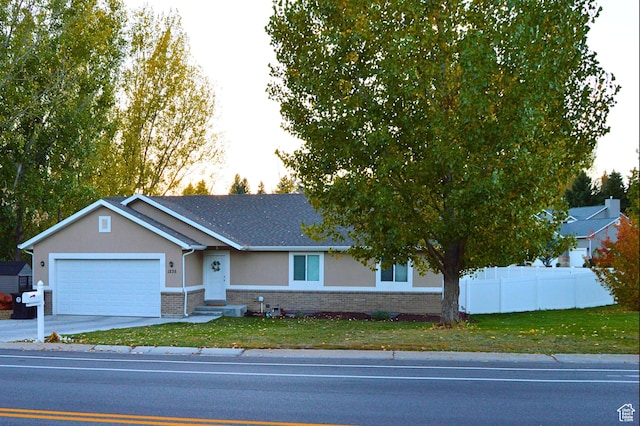 single story home featuring driveway, stucco siding, fence, brick siding, and a garage
