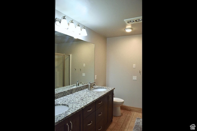 bathroom featuring a sink, a shower stall, toilet, baseboards, and wood finished floors