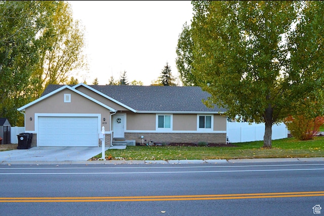 ranch-style home with driveway, stucco siding, fence, brick siding, and a garage