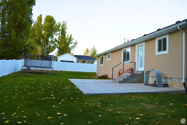 view of yard with a trampoline, a fenced backyard, and a patio area