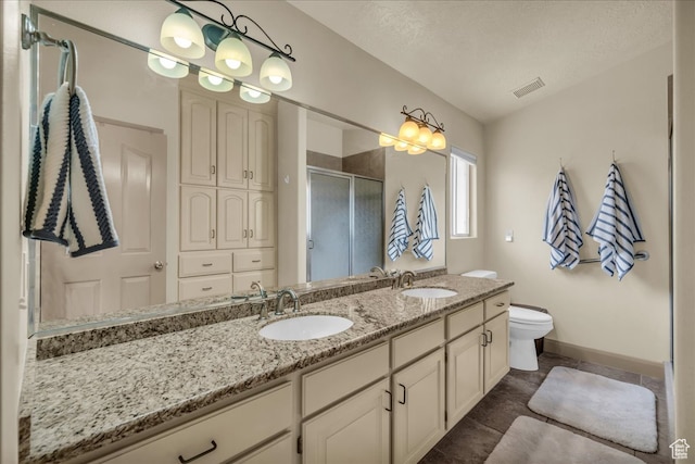 bathroom featuring a textured ceiling, toilet, tile patterned floors, walk in shower, and vanity