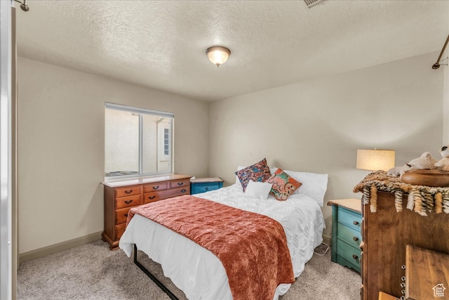 bedroom featuring a textured ceiling and light colored carpet