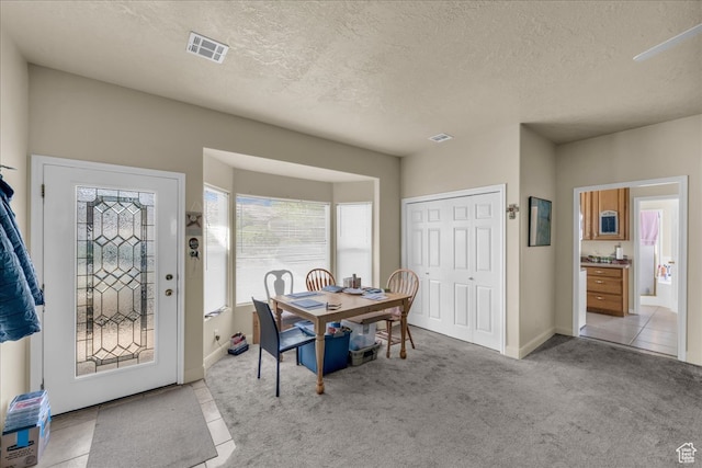carpeted dining room featuring a textured ceiling