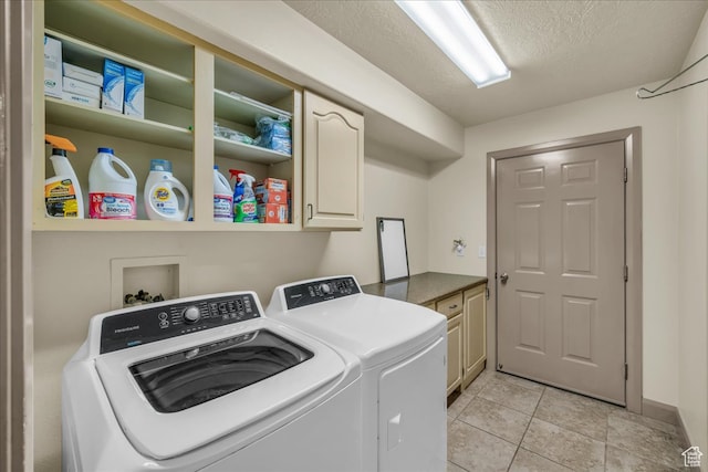 laundry room featuring washer and clothes dryer, a textured ceiling, light tile patterned floors, and cabinets