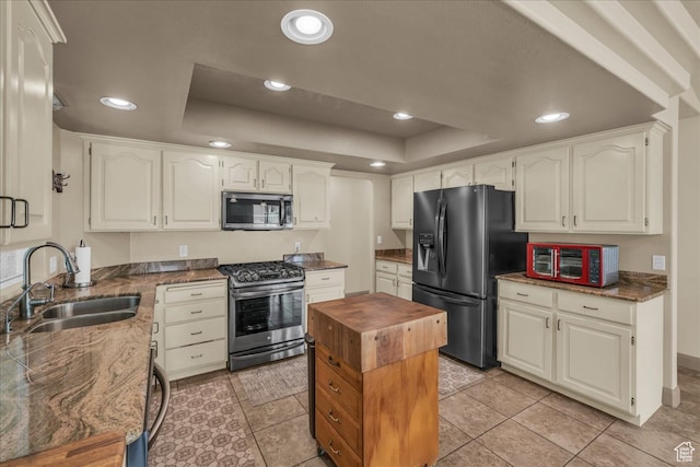 kitchen with sink, white cabinets, stainless steel appliances, and a raised ceiling