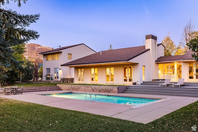671 N Freeze Creek Cir, Emigration Canyon, UT 84108 - back of property at dusk featuring an outdoor pool, stucco siding, french doors, and a chimney
