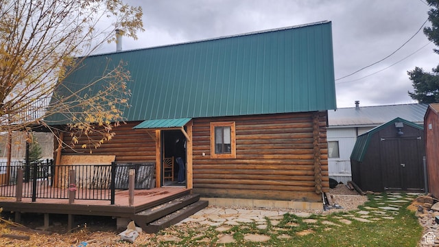 rear view of house featuring metal roof, a storage shed, a deck, log siding, and an outdoor structure