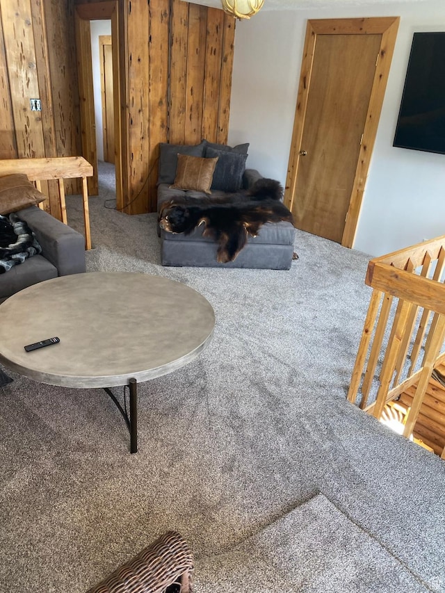 carpeted living room featuring wood walls