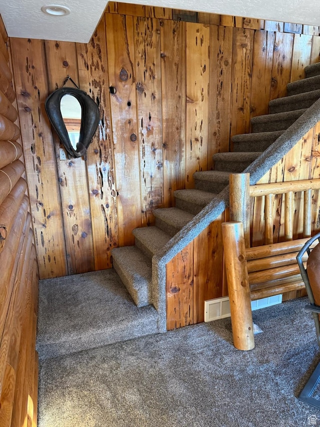 staircase with carpet floors and wood walls