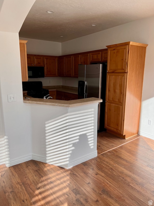 3119 N Sage Loop Unit F3, Lehi, UT 84043 - kitchen featuring black appliances, kitchen peninsula, a textured ceiling, and light wood-type flooring