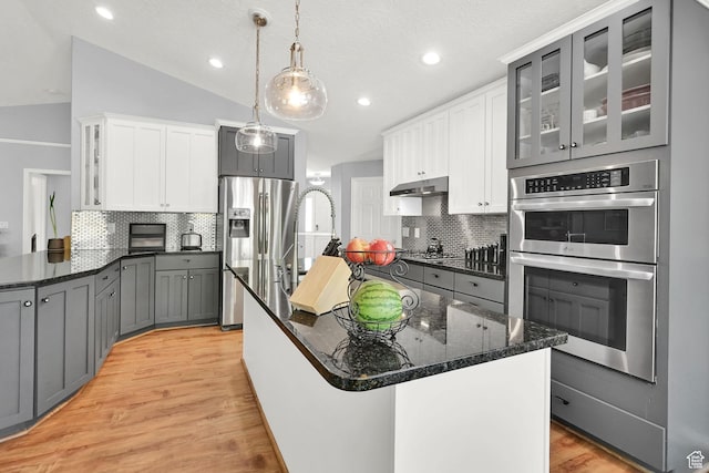 3937 N Patio Springs Dr, Eden, UT 84310 - kitchen featuring appliances with stainless steel finishes, backsplash, light wood-style floors, dark stone countertops, and recessed lighting