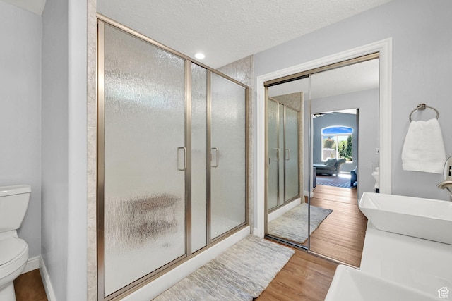 3937 N Patio Springs Dr, Eden, UT 84310 - full bathroom with toilet, wood finished floors, a shower stall, a textured ceiling, and baseboards