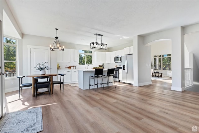 kitchen featuring a breakfast bar area, light hardwood / wood-style flooring, a center island, white cabinets, and appliances with stainless steel finishes