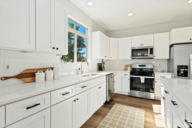 kitchen with stainless steel appliances, backsplash, sink, white cabinets, and dark hardwood / wood-style flooring