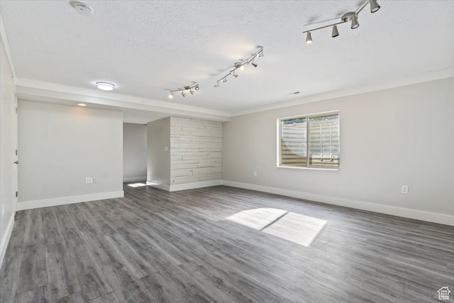 empty room with a textured ceiling, track lighting, and dark hardwood / wood-style floors