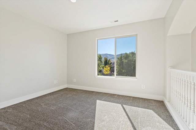 spare room with a mountain view and carpet floors