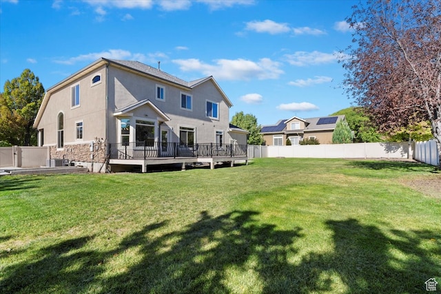 back of house with a deck and a lawn