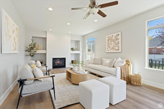 living room with a large fireplace, plenty of natural light, and light wood-type flooring