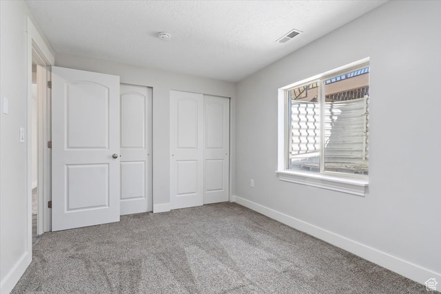 unfurnished bedroom with a textured ceiling and carpet floors