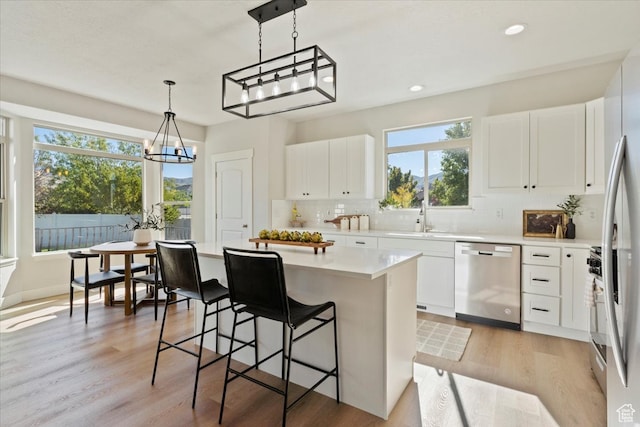kitchen with white cabinetry, light wood-type flooring, appliances with stainless steel finishes, and pendant lighting