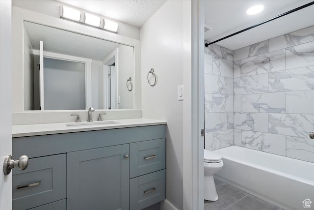 full bathroom with toilet, tile patterned flooring, tiled shower / bath combo, vanity, and a textured ceiling